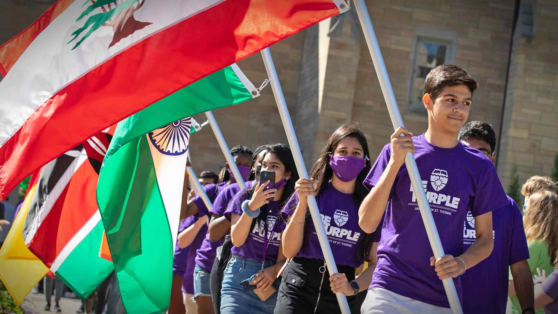 International students carry flags through the arches