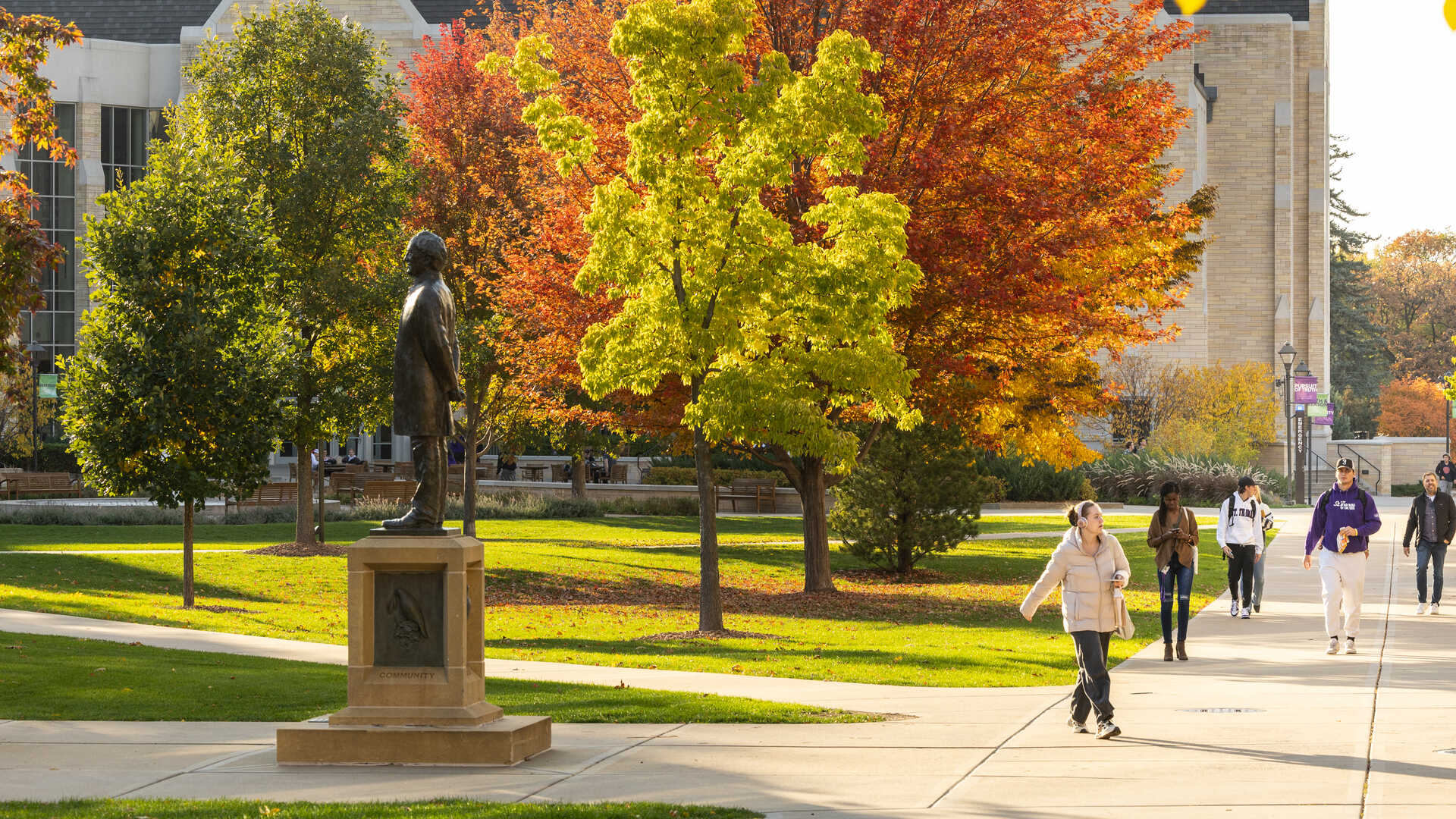 Students walk near autumn trees on campus