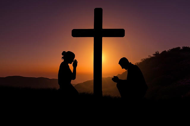 Image of the Cross with 2 people praying