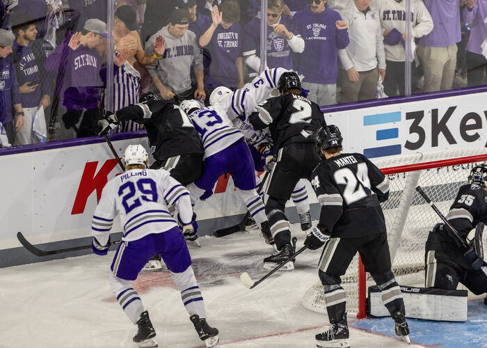 hockey players battle for the puck behind the net