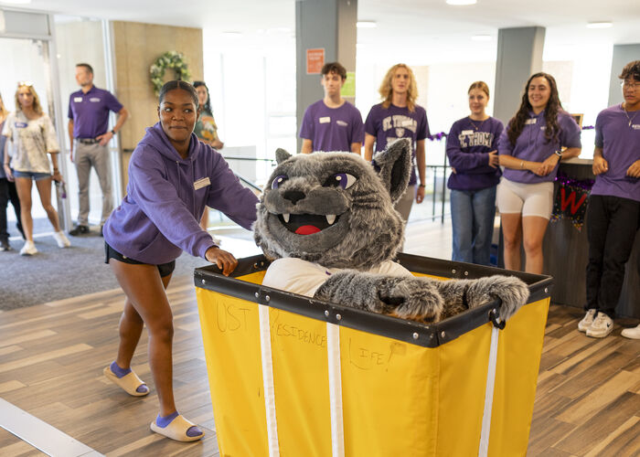 Student pushing Tommie in a move-in cart