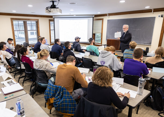 professor lectures in a small classroom with windows