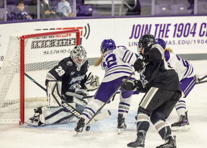 hockey player attempts a score at the net