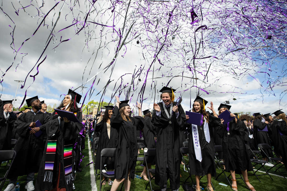 graduating students laugh as confetti falls around them