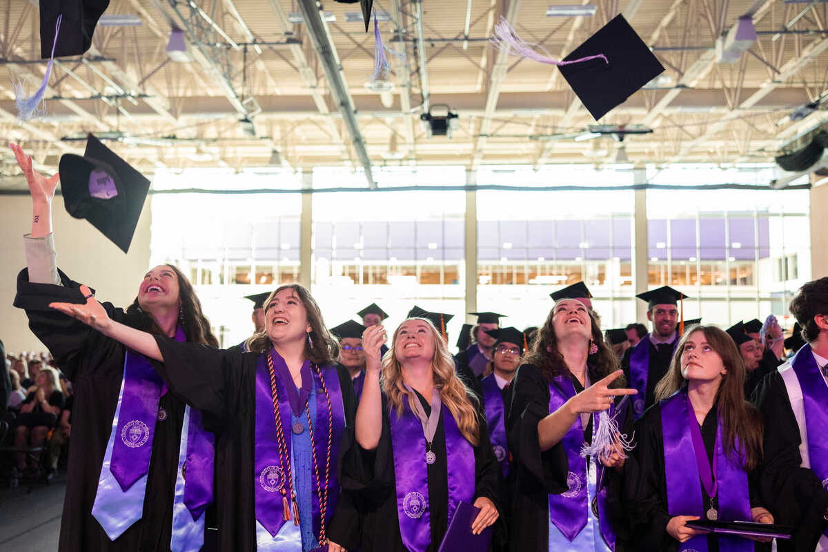 A group of St. Thomas students throw their grad caps in the air after graduation ceremony