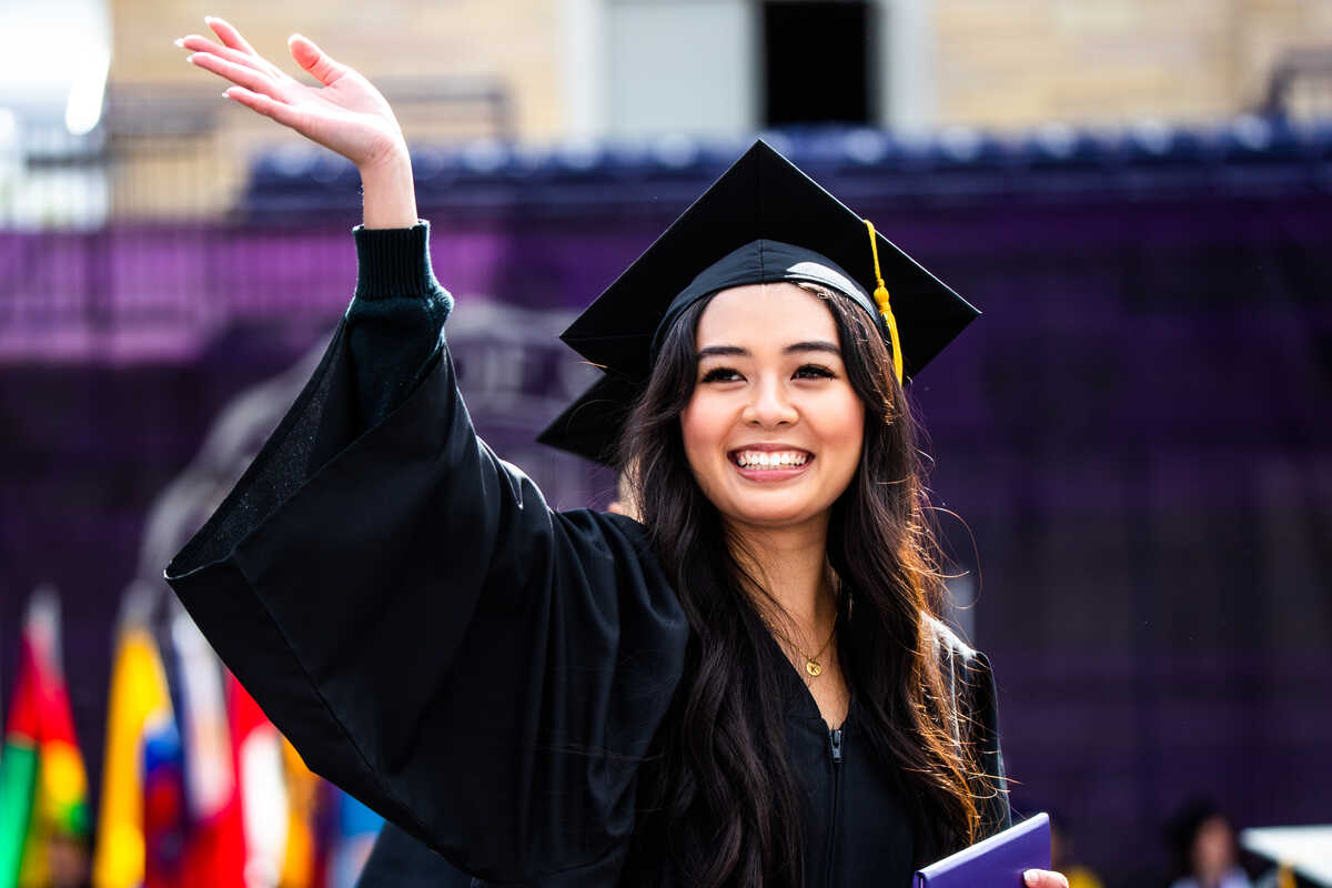 A student waves to the crowd at the undergraduate commencement ceremony in St. Paul on Saturday, May 21, 2022.