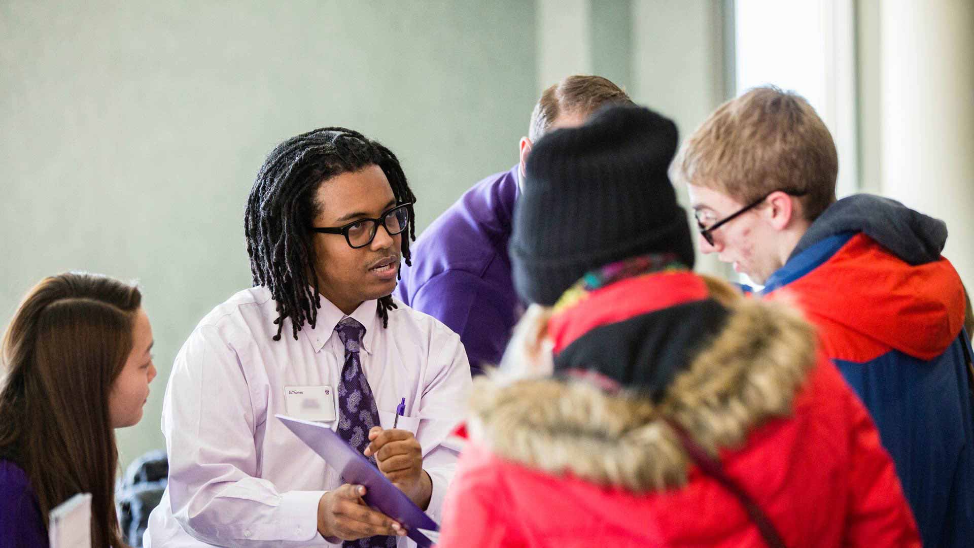 Admissions Counselor Abeye Cherinet (second person on the left) helps prospective students check in during the kickoff of the Tommie Overnight event.
