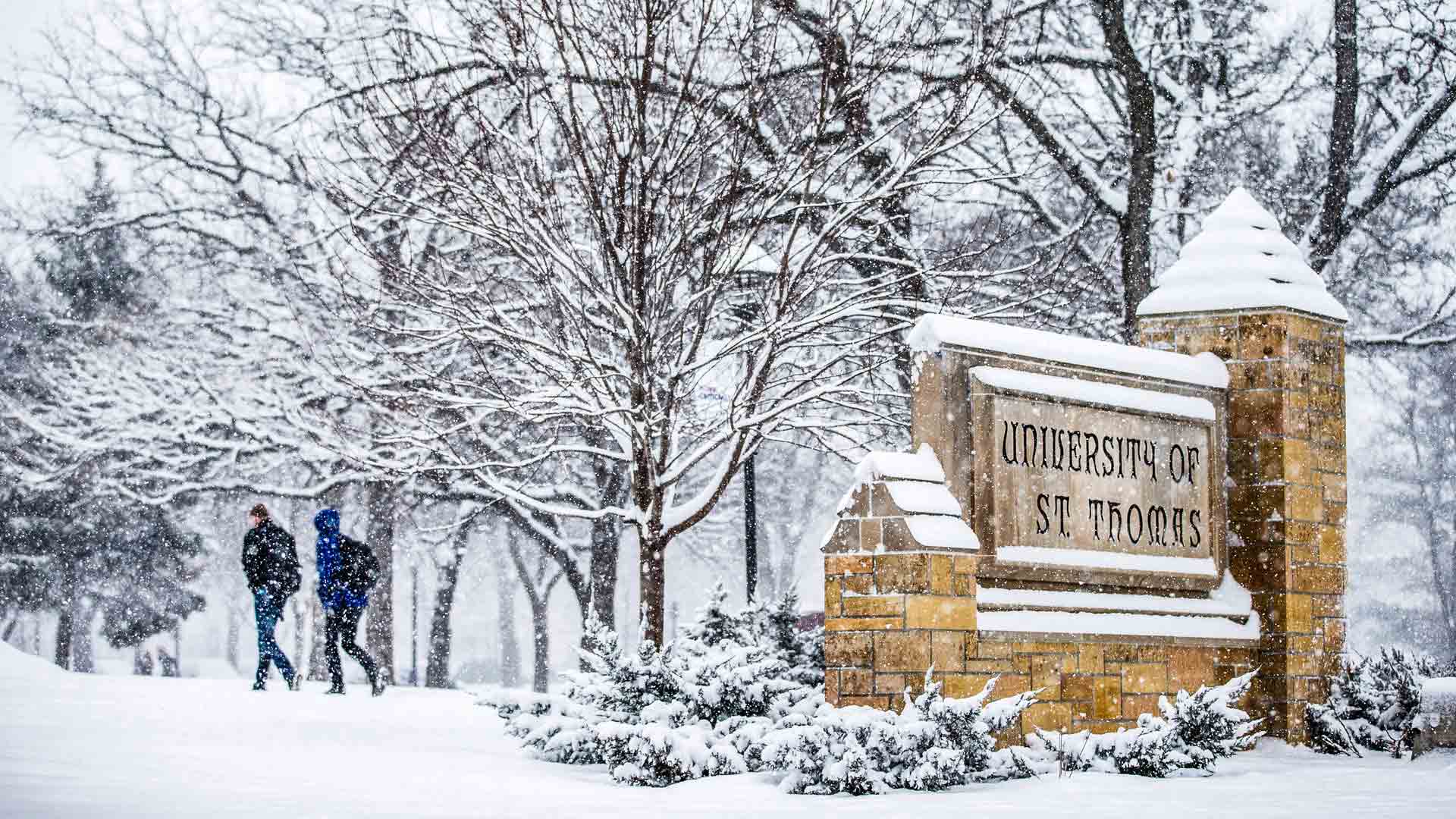 University of St. Thomas stone sign covered in snow.