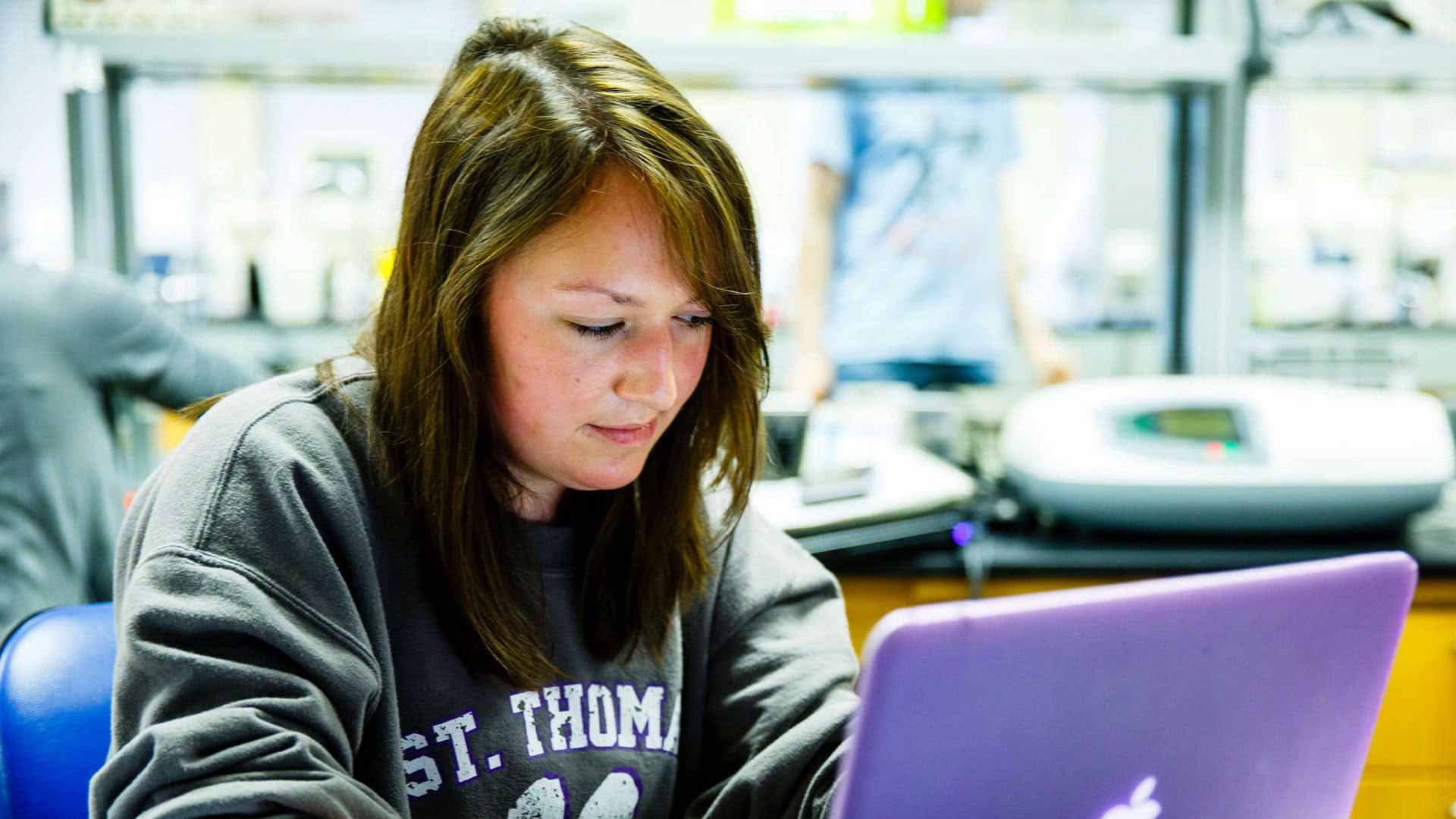 Student Tess King types on purple laptop computer during a biochemistry lab.