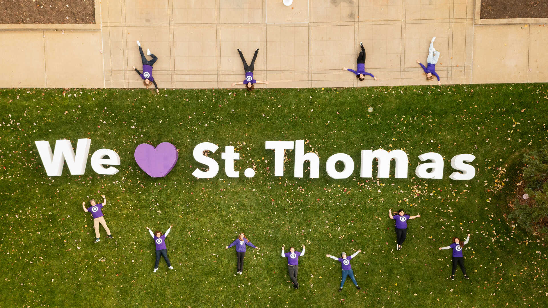 We Heart St. Thomas sign with students laying around it in the grass