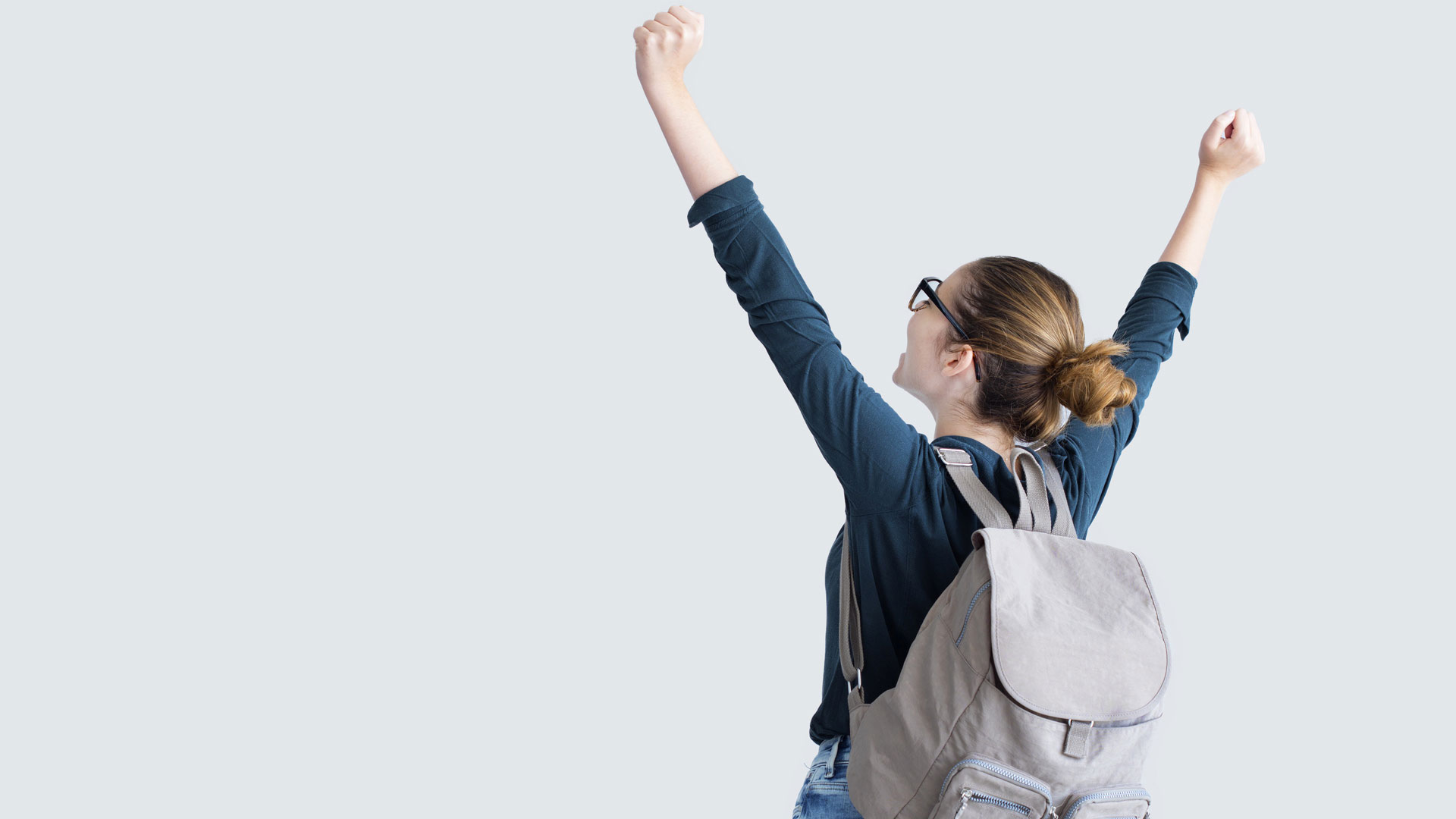Female student wearing backpack facing away with arms raised.