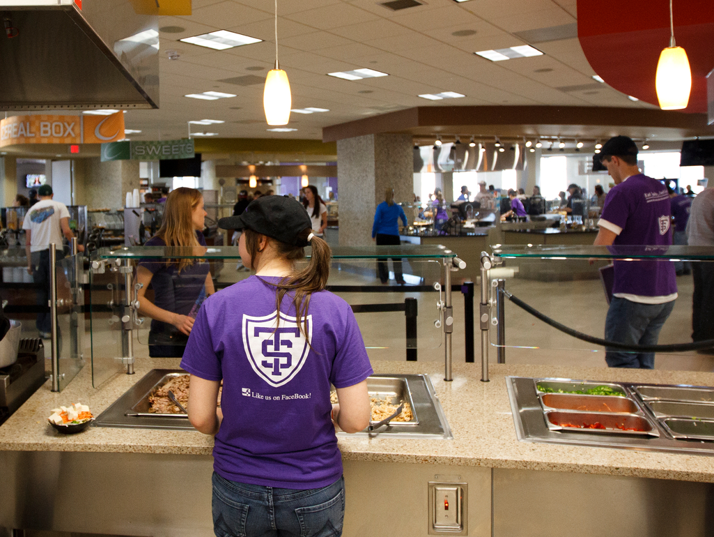 the back of a student serving food from a dining station