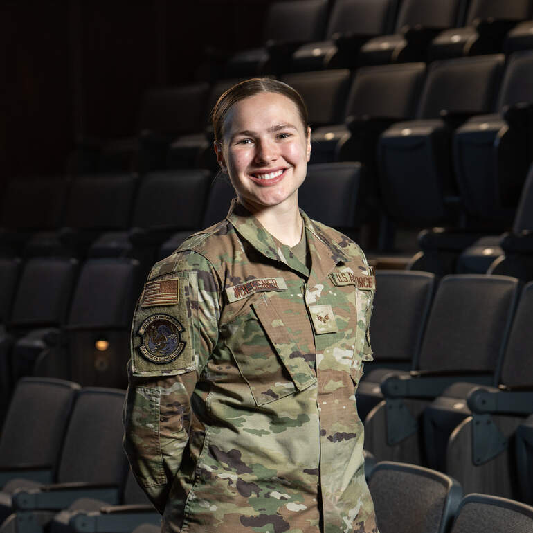 Sophie Woessner standing in physics auditorium in her Air National Guard uniform