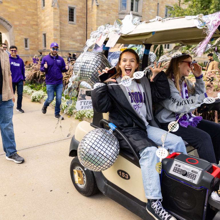 student celebrating in golf cart during homecoming