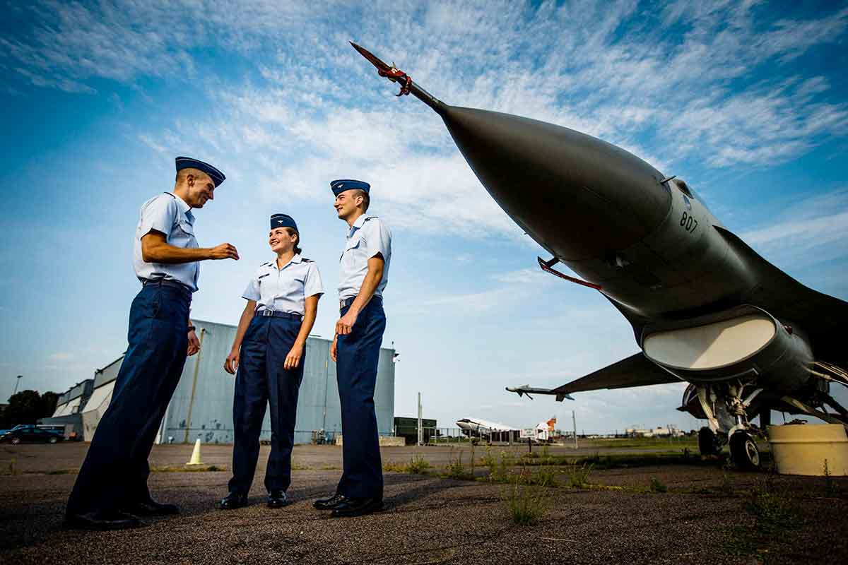 Air Force ROTC cadets talk in front of a F-16 Fighting Falcon jet.