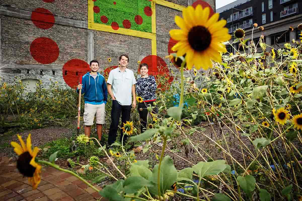 Hunter Gaitan '15 (Biology), Biology Professor Adam Kay and Amanda Lovelee, St. Paul City Artist, pose for a portrait at the Urban Flower Field at Pedro Park at 10th and Robert Streets in downtown St. Paul