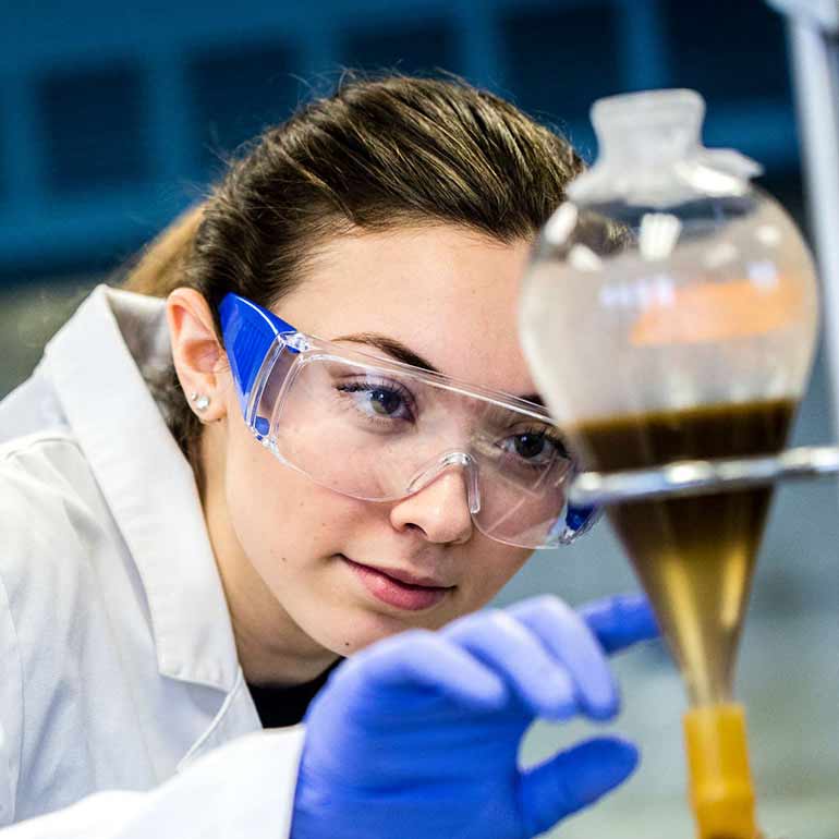 Geology student Sarah Howe examining a solution in a lab