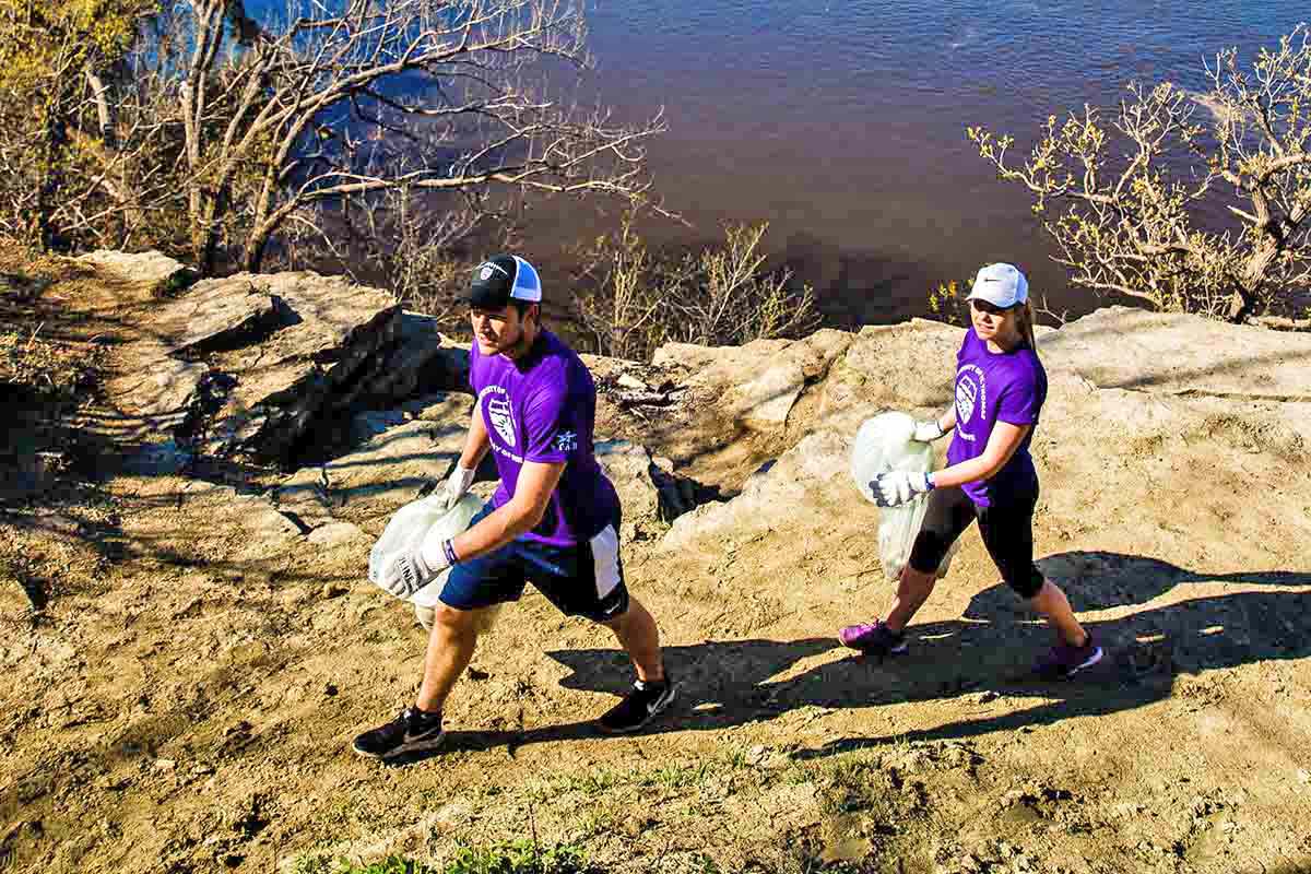 Students pick up trash along the shore of the Mississippi River in St. Paul during a St. Thomas Day of Service.