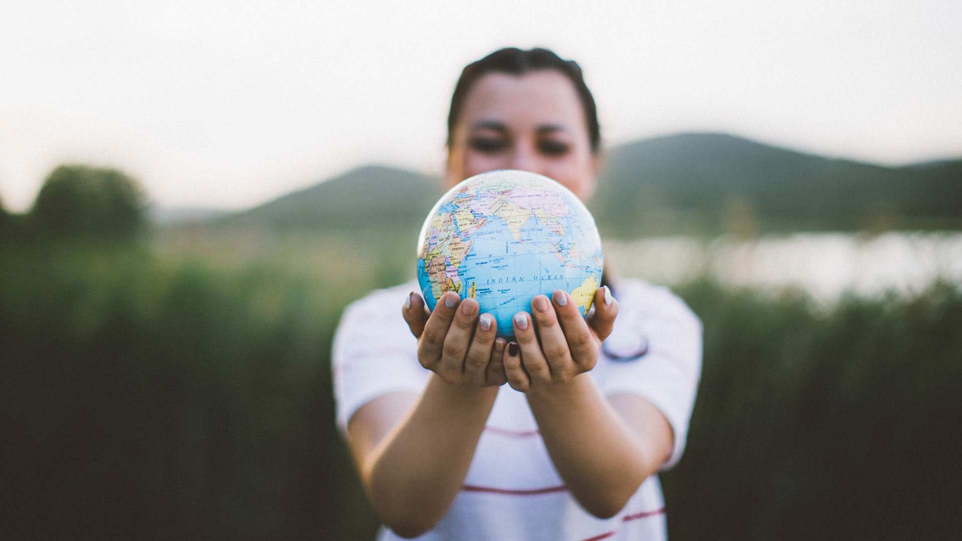 An individual holds a globe in outstretched hands. 