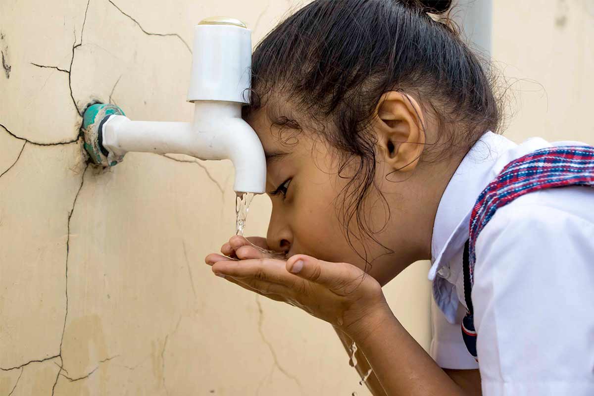 Young child drinks clean water from faucet in Iraq
