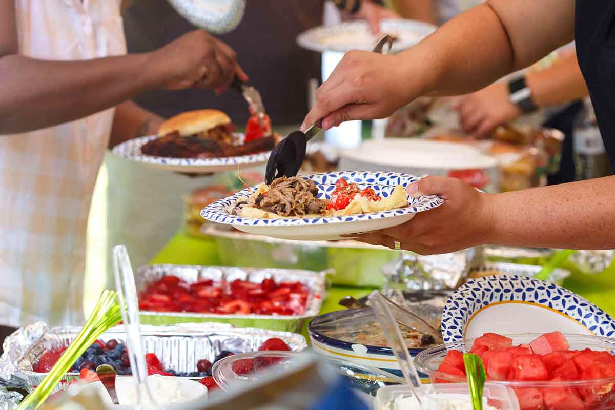 People add food to their plates at a potluck meal.