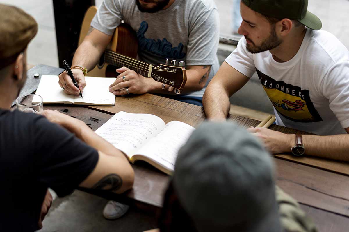 A group sits around a table, while writing music.
