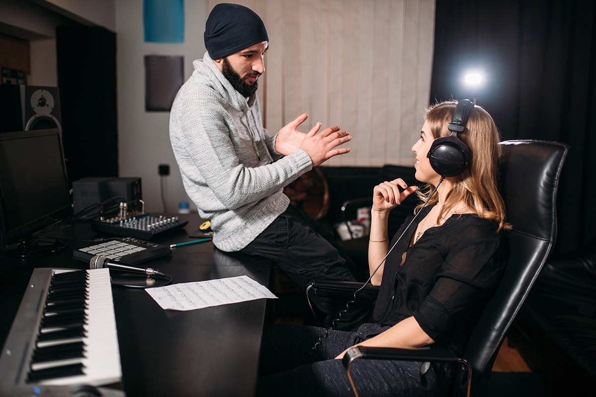 Individuals communicating in a recording studio. 