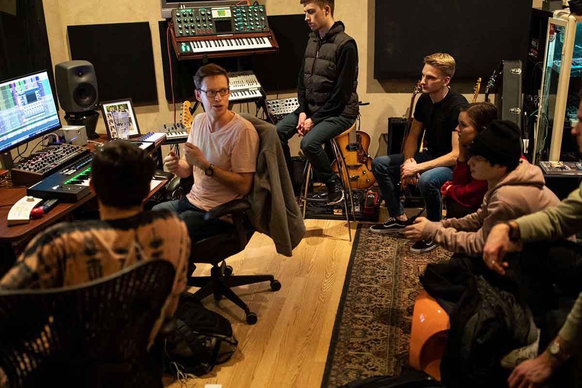 Professor talks with students during a music class in a studio.