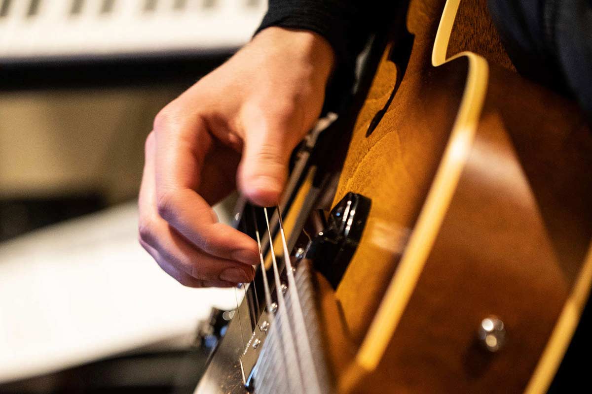 A close-up of a hand playing a guitar.