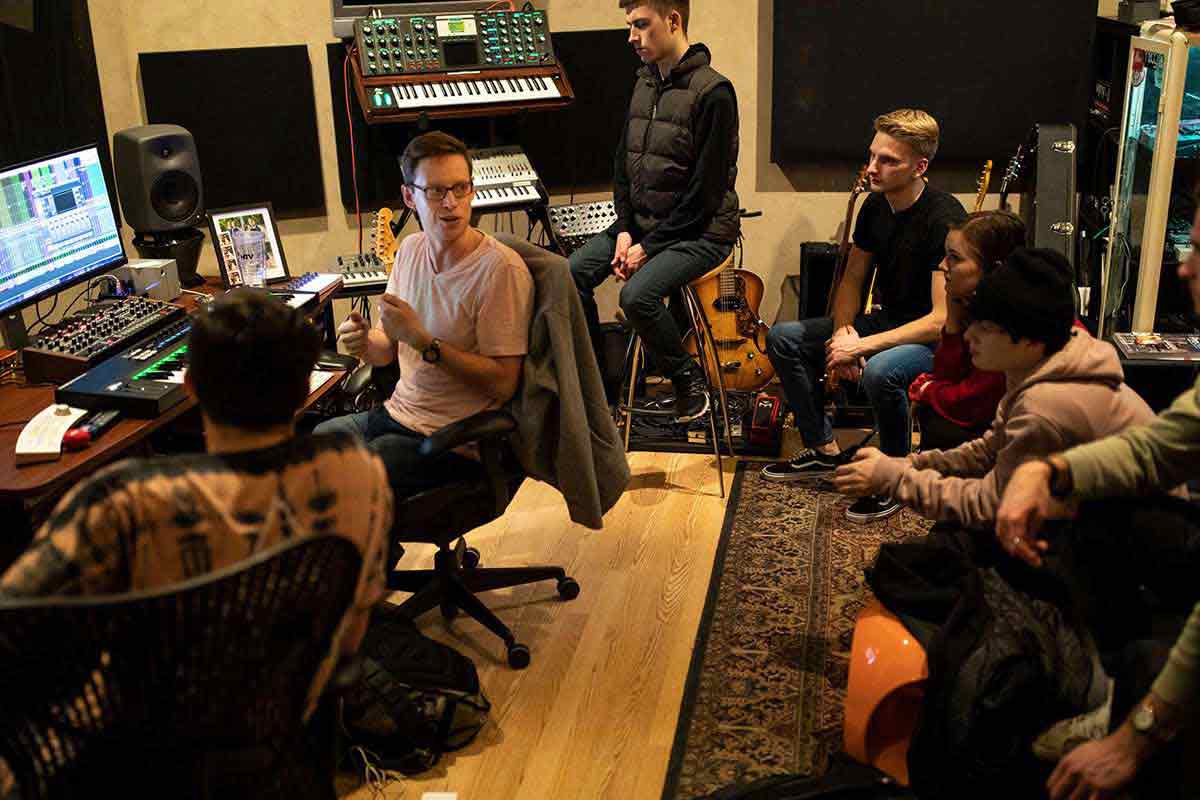  A professor talks with students in a music studio during a music class.