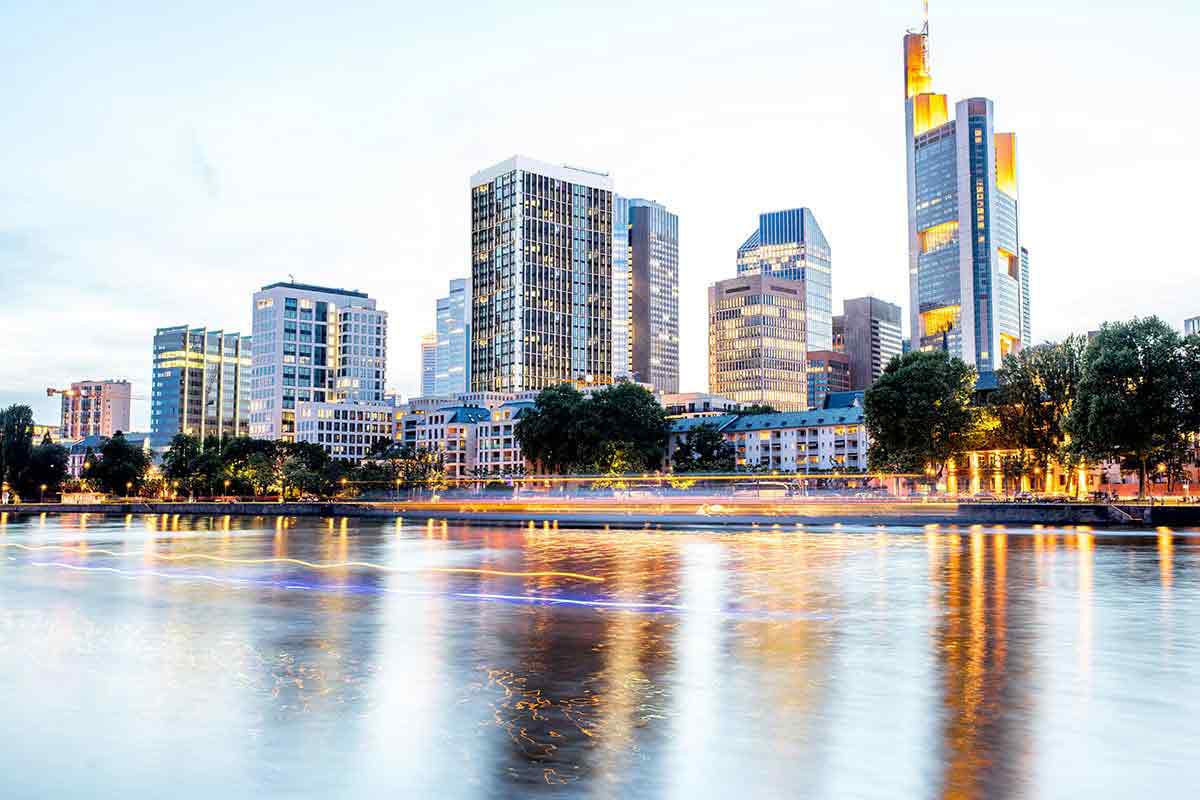 Skyscrapers lit up over an evening sunset on a lake.