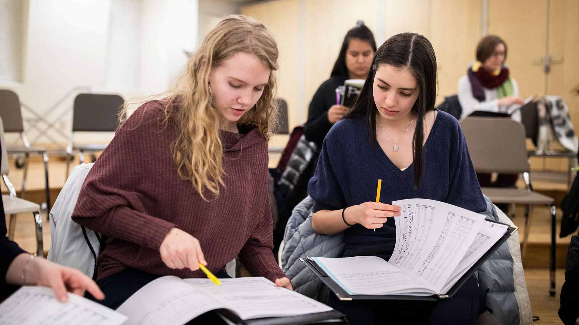 Two students review pieces of choir music.