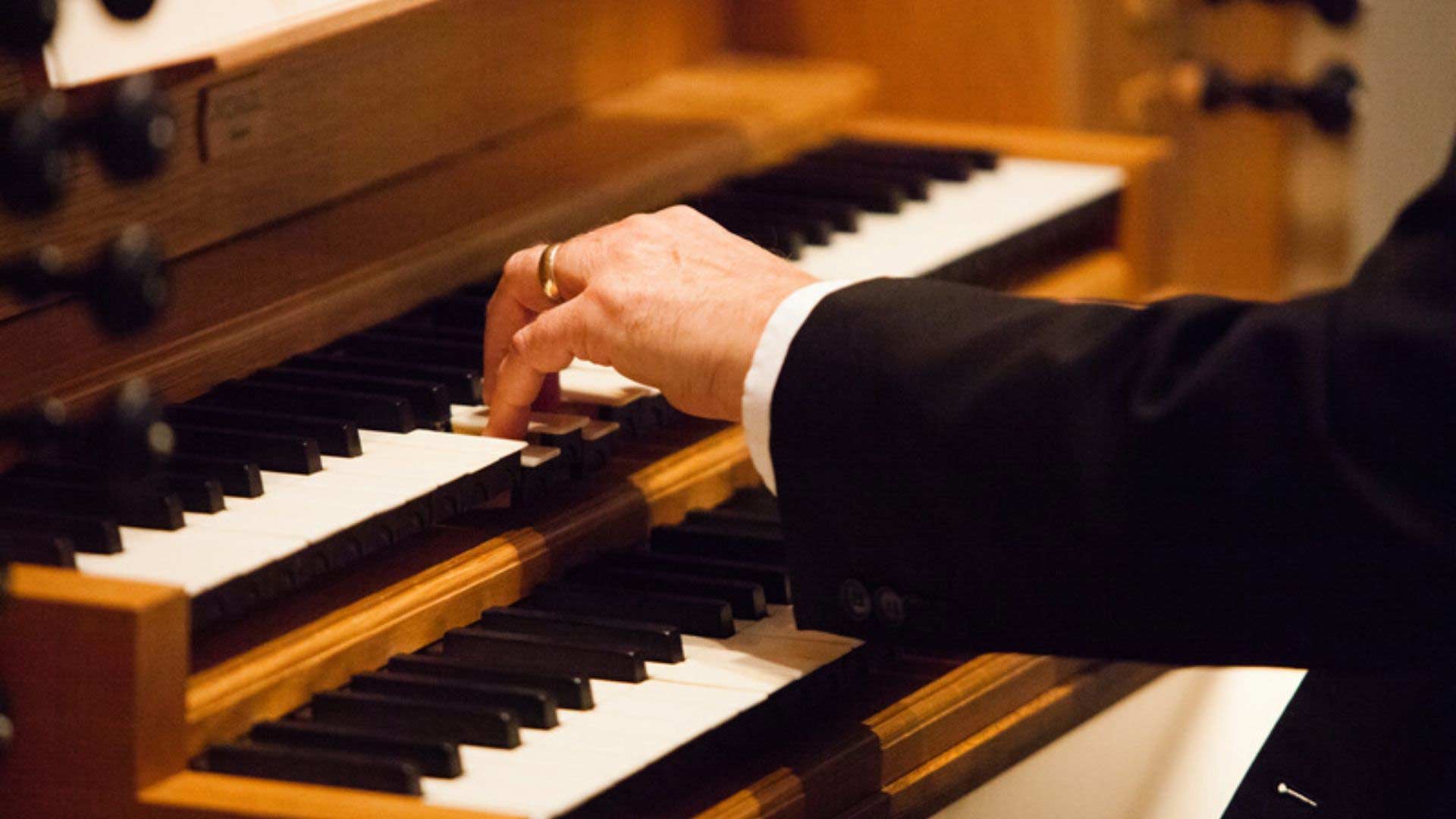 Close-up of a hand playing an organ.