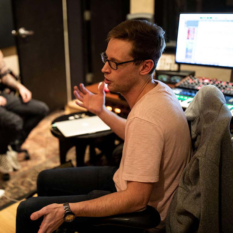 Brian Casey talk with students in a music studio.