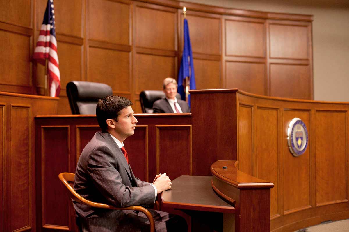 A student is on the stand in court room during a mock trial.