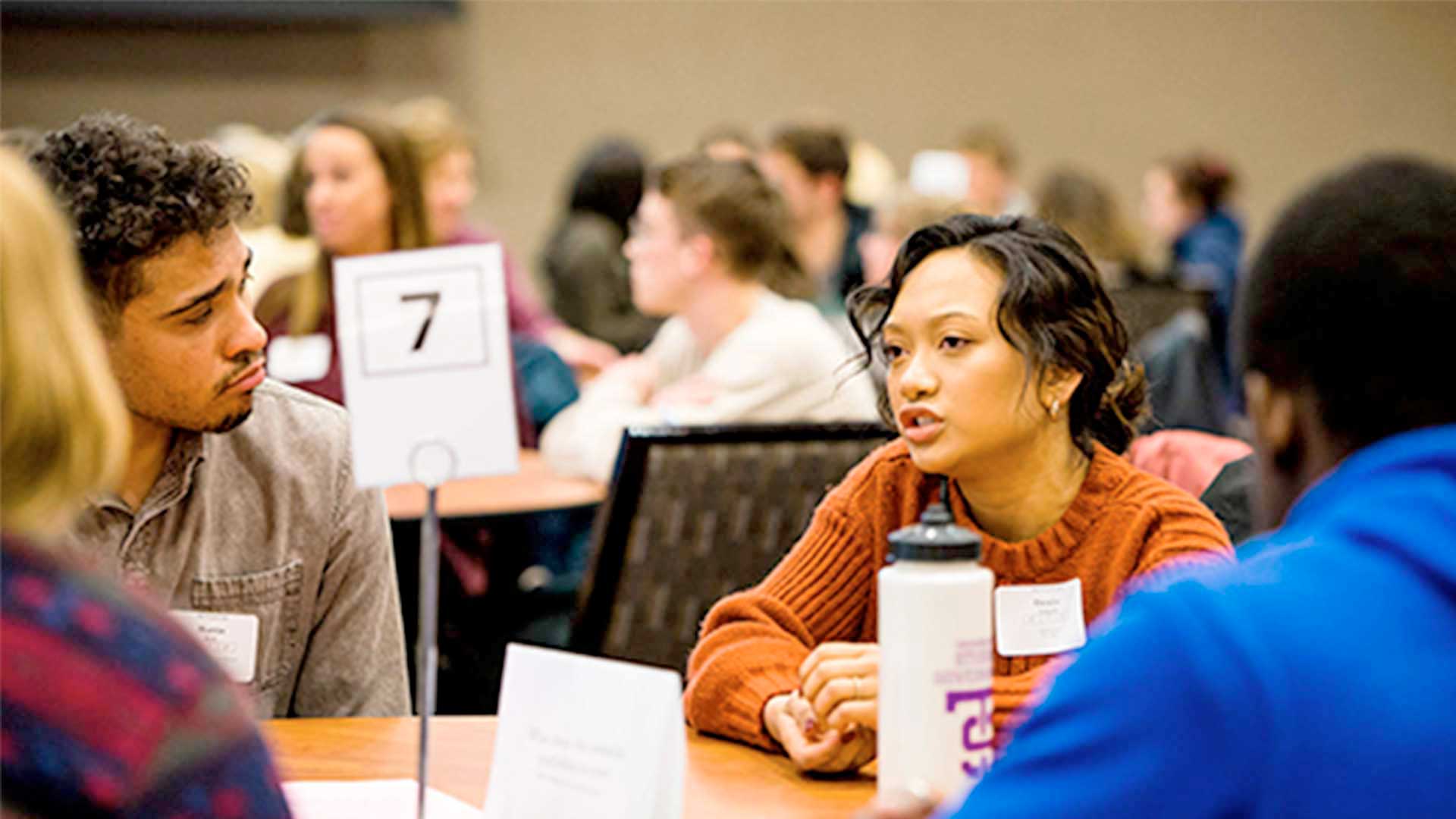 Students converse at a table during a conference.