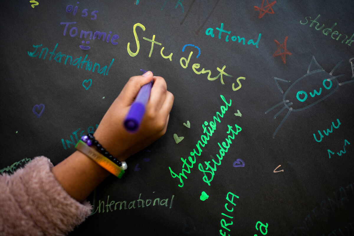 Student's hand writing on a blackboard