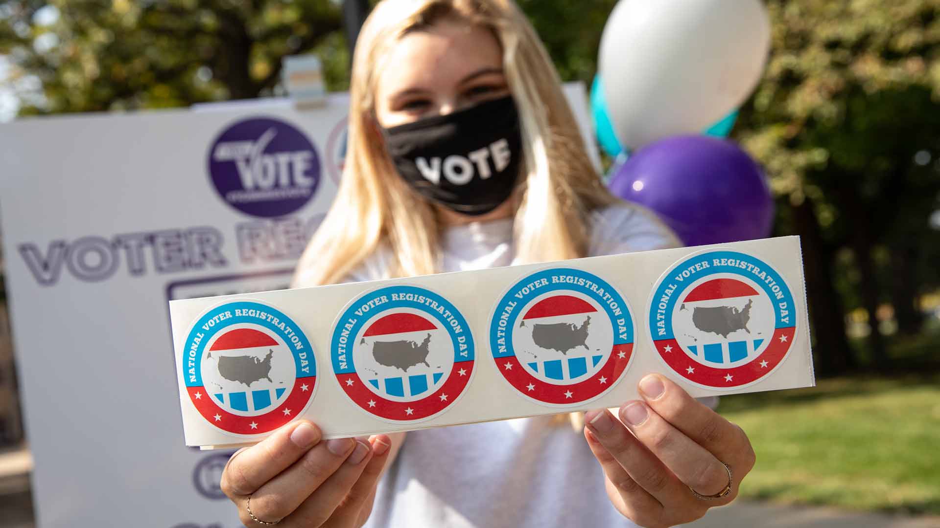 Student holding "voter" stickers