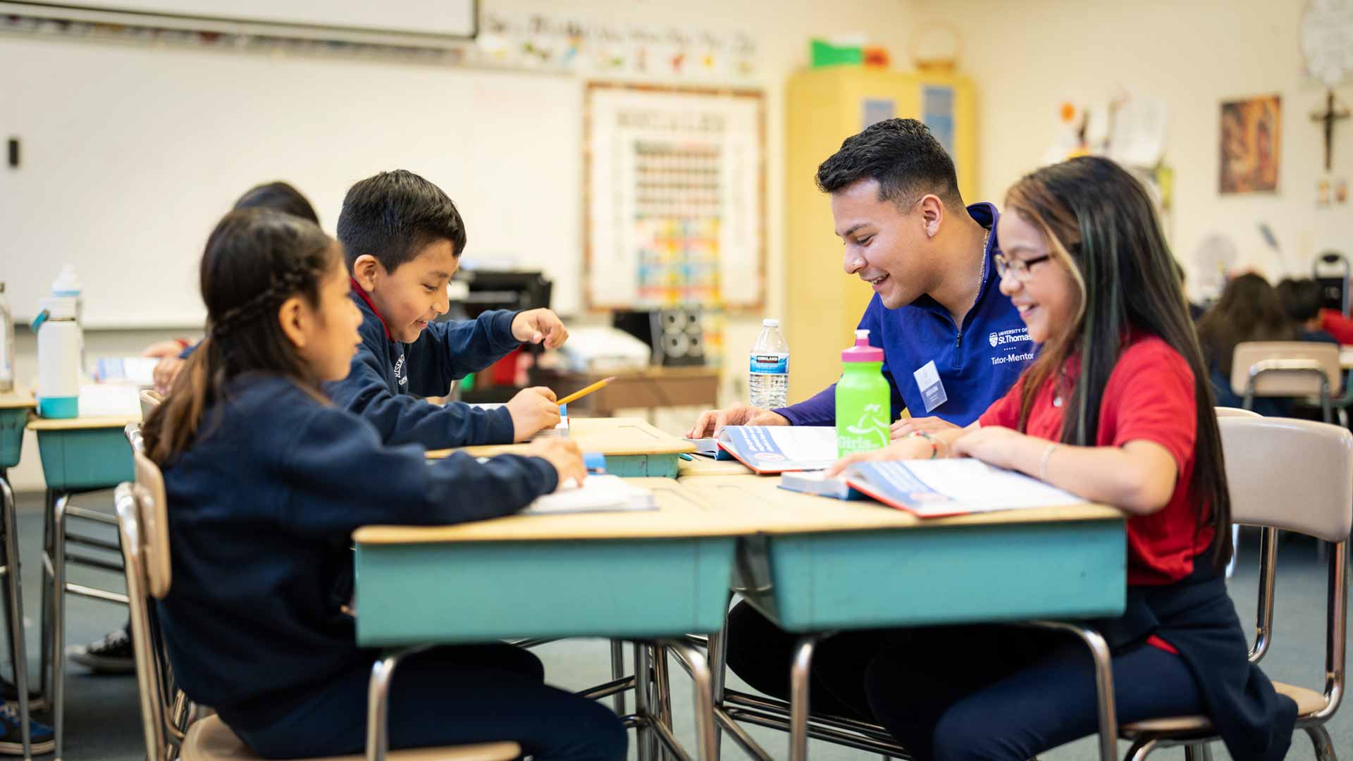 Volunteer works with young students at desk