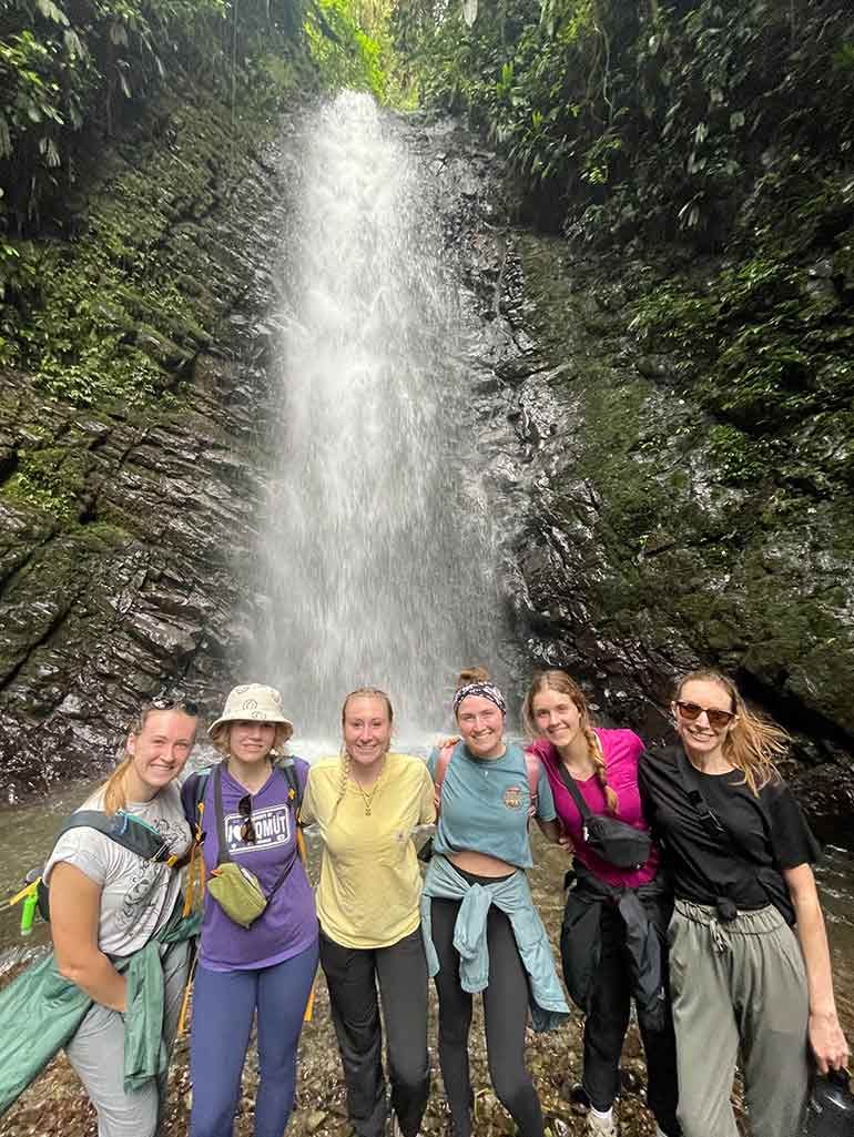 Students take group photo in front of waterfall