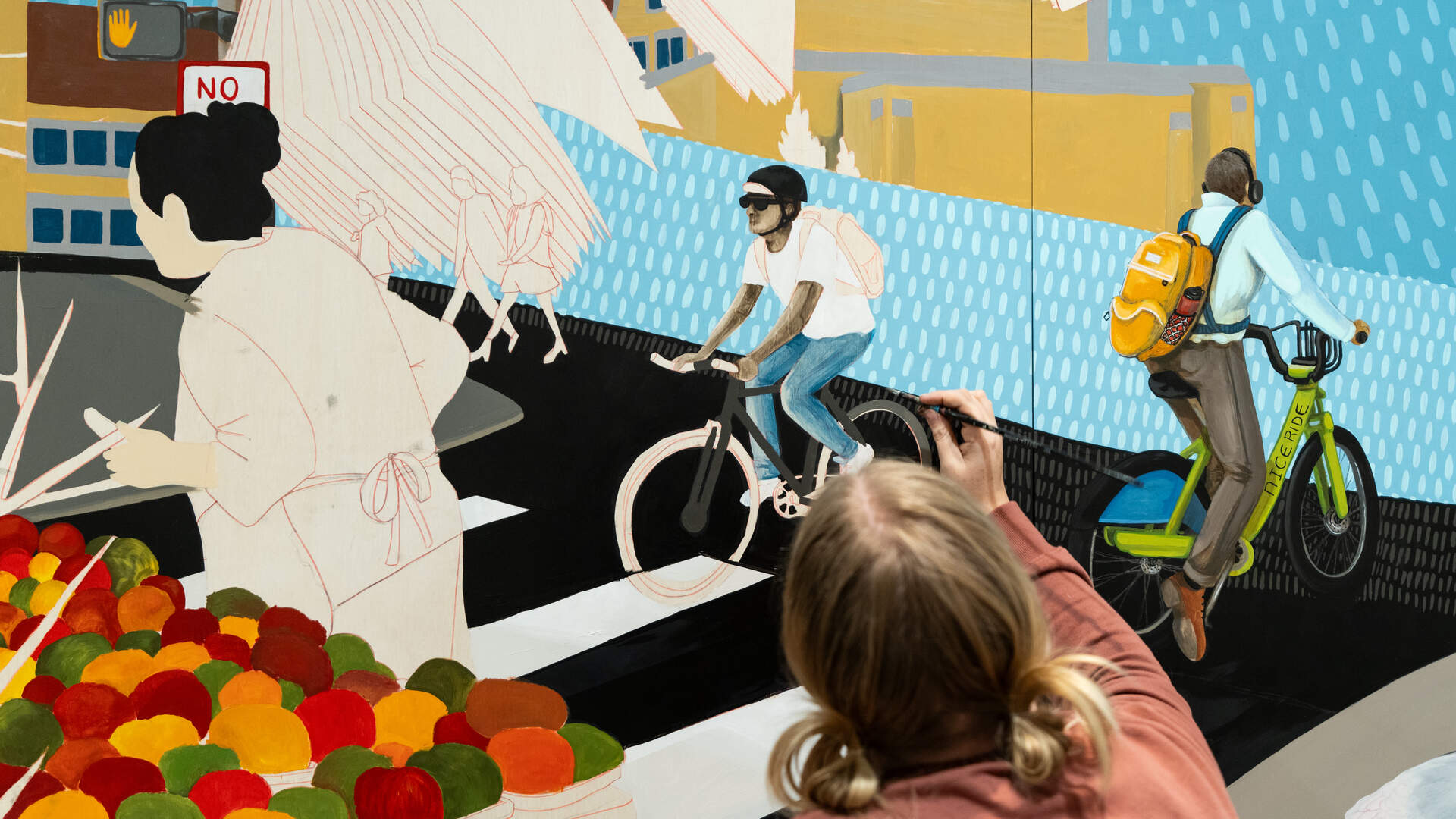 Artist Jessica Turtle painting a mural of bikes and pedestrians.
