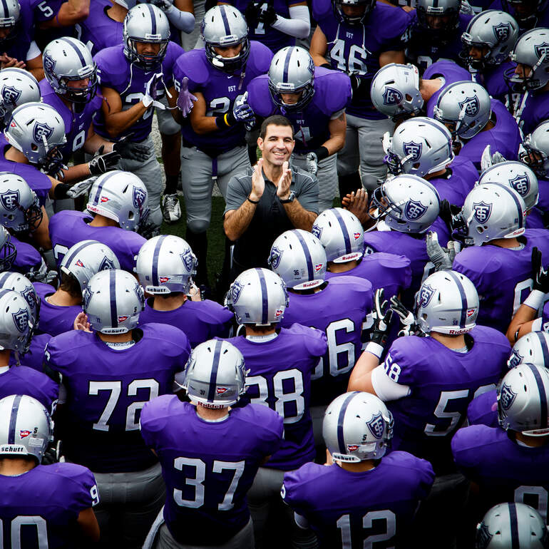 Tommie football players gather around a coach