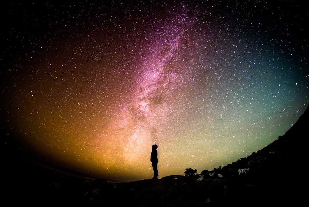silhouette of man looking up at the cosmos