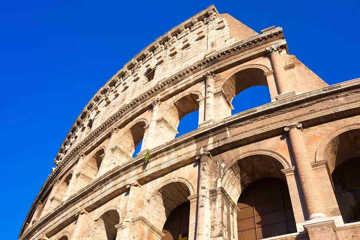 A portion of the Colosseum in Rome is shown with a blue sky as a back drop.