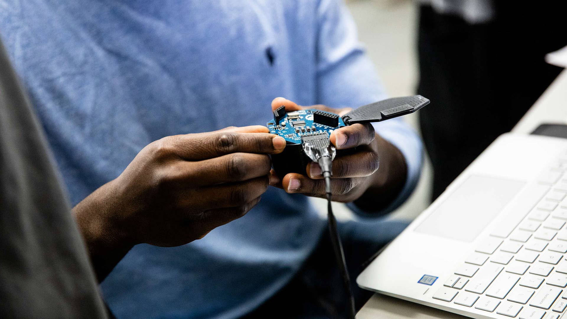 A student holds the wireless module being used for a senior design project.