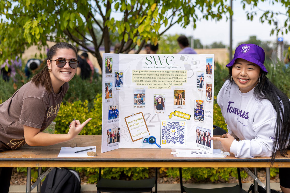Students display a poster at a St. Thomas activities fair.