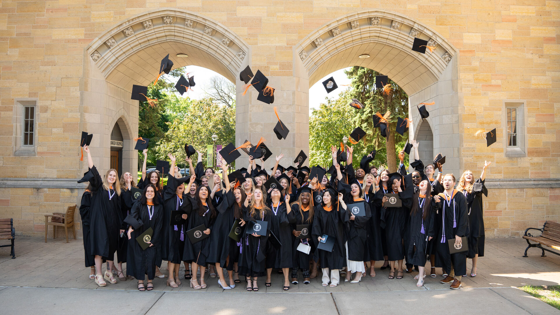 Graduates throw their caps in the air in front of the St Thomas arches