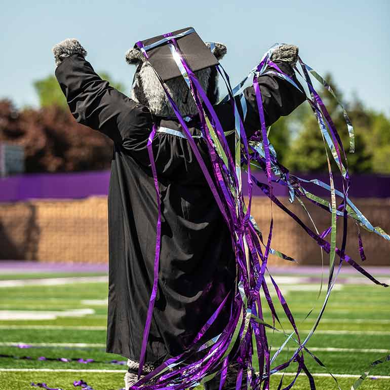 Tommie mascot covered in streamers at commencement ceremony.