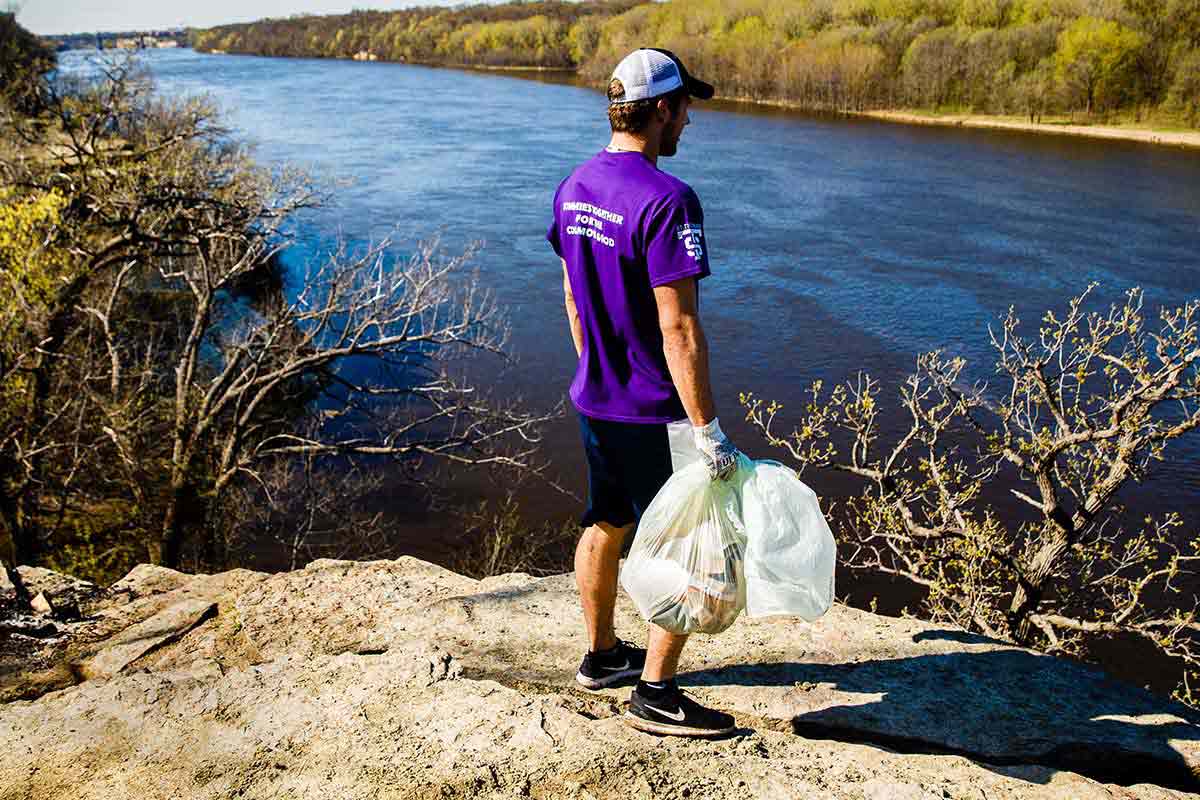Student picking up trash by river