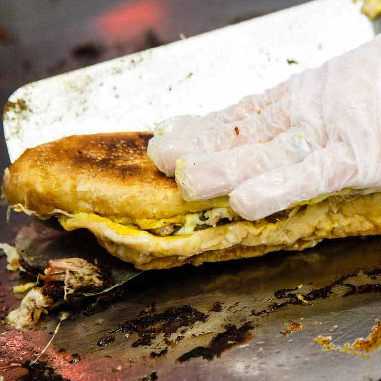 Cubano sandwich served with gloved hands